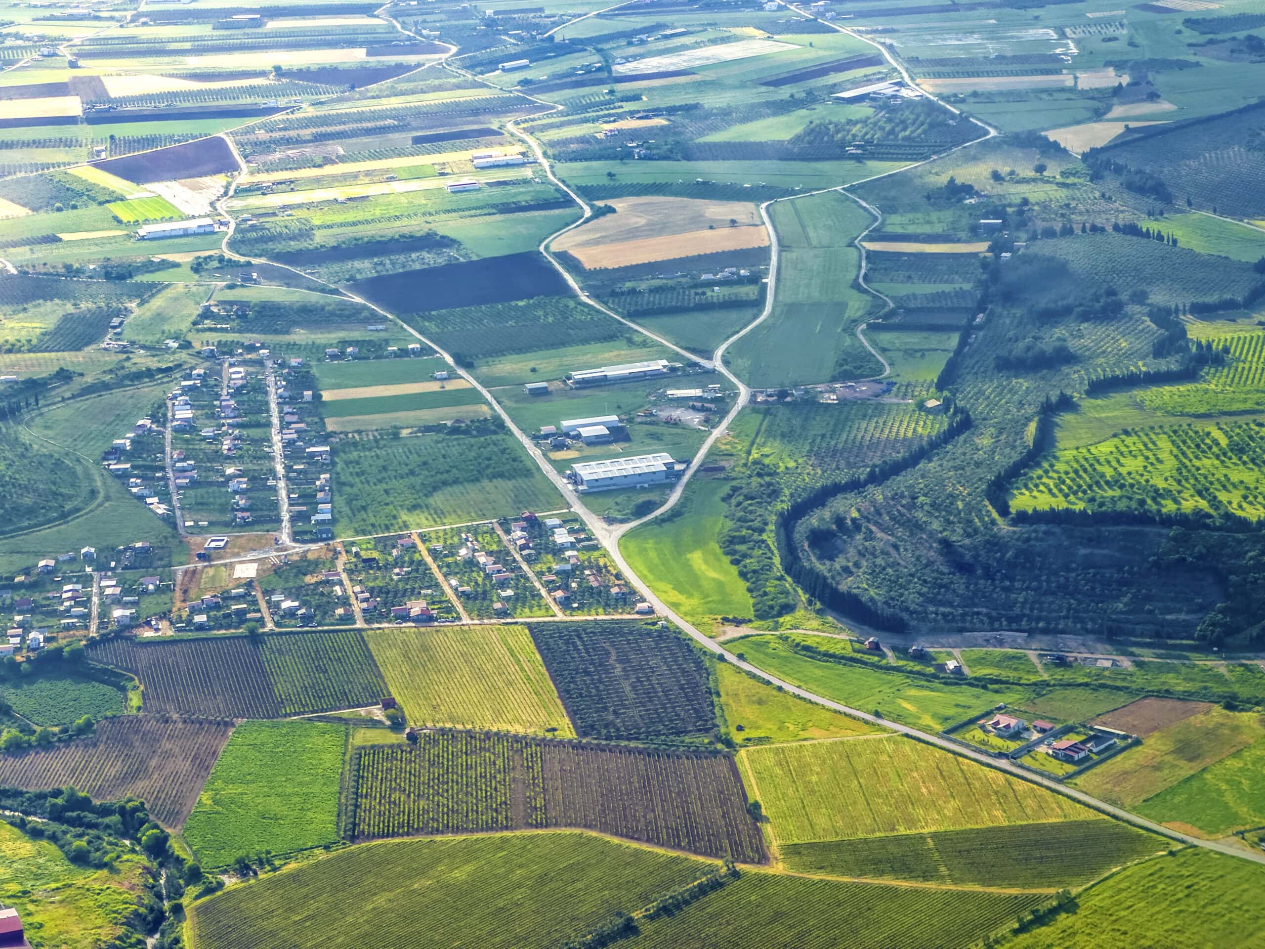 Aerial view of diverse land types including agricultural, residential, and recreational properties, representing land for sale near me.