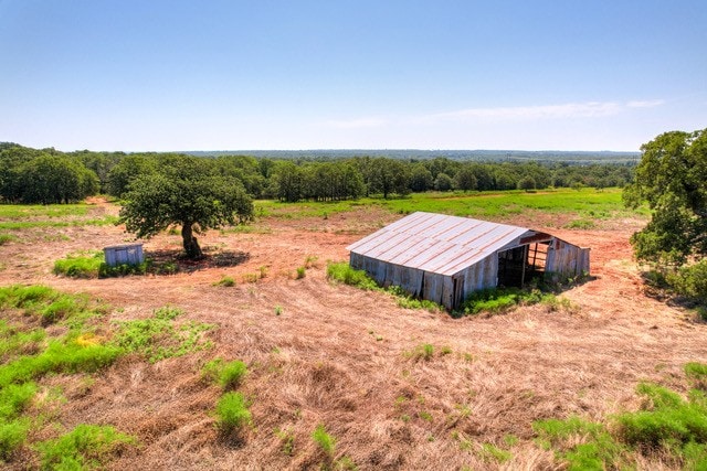 Land for sale in Oklahoma with a barn and scattered trees under a clear sky.